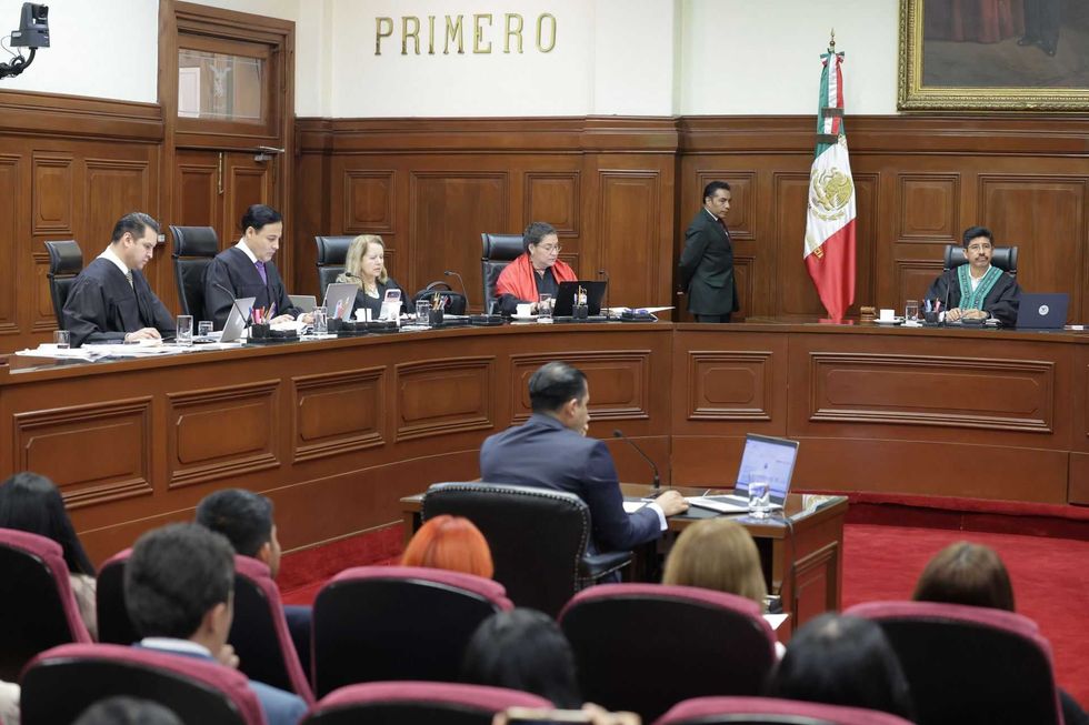 Judges in a courtroom with an audience, Mexican flag behind one judge.