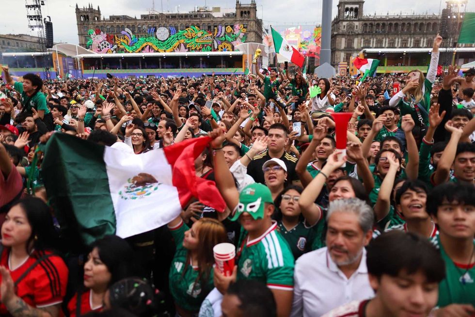 Large crowd celebrating with Mexican flags and jerseys in a colorful outdoor event.