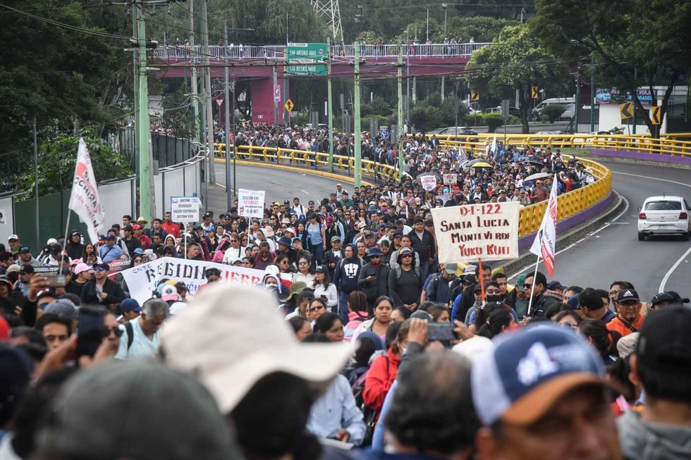 Large crowd marching on a city road with banners and signs.