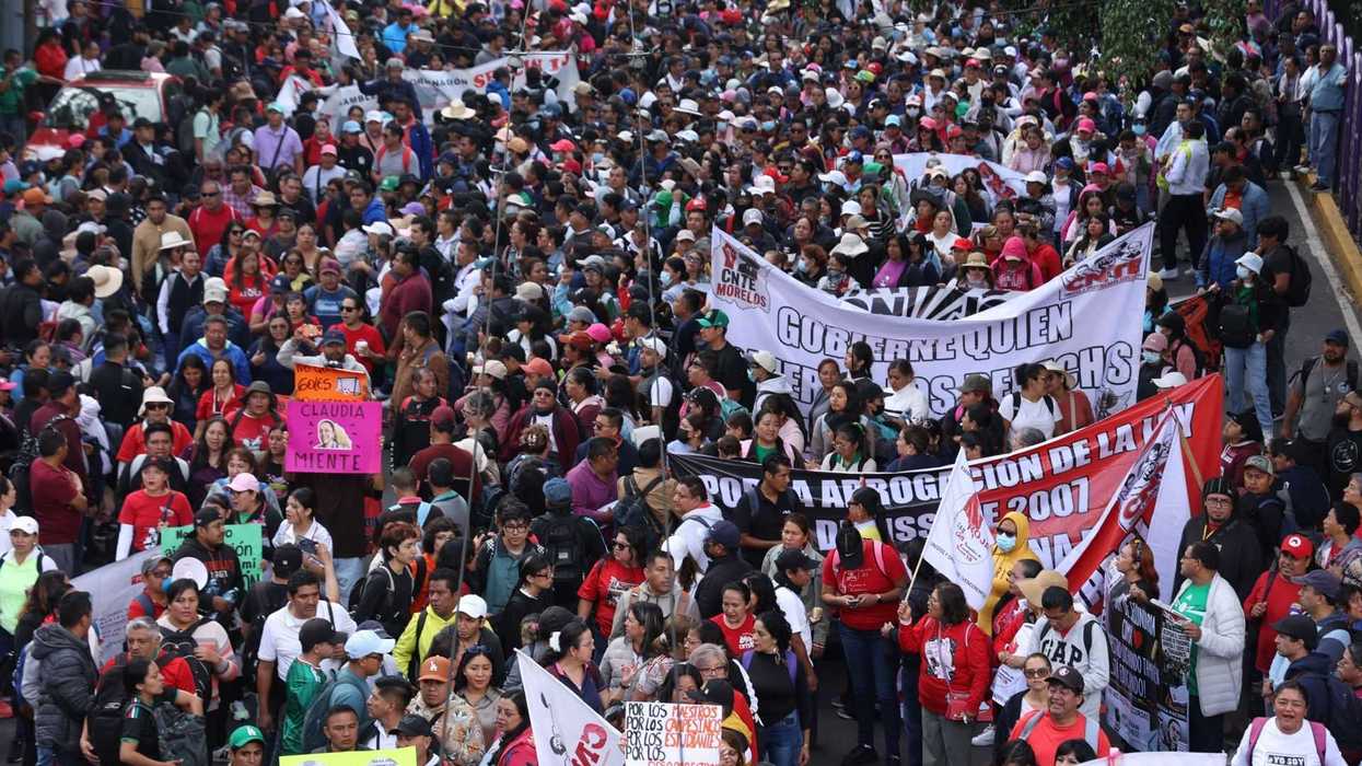 Large crowd of protesters with banners marching on a street.