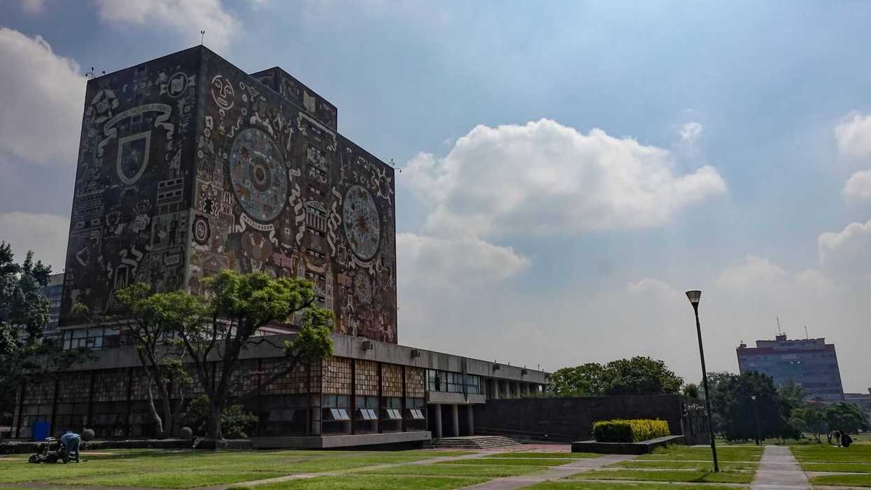 Library building with murals and green lawn under a partly cloudy sky.