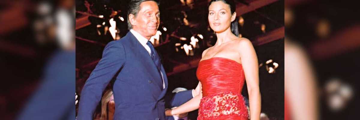 Man in suit and woman in red dress at an elegant, dimly-lit event.