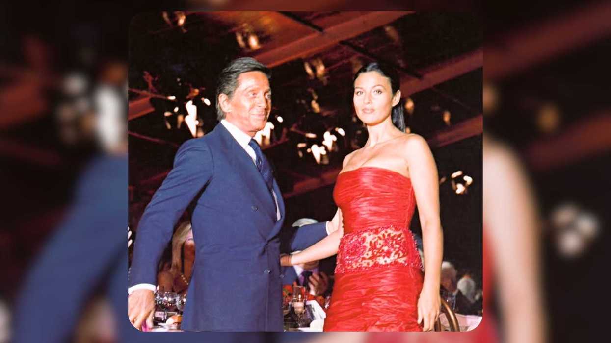 Man in suit and woman in red dress at an elegant, dimly-lit event.