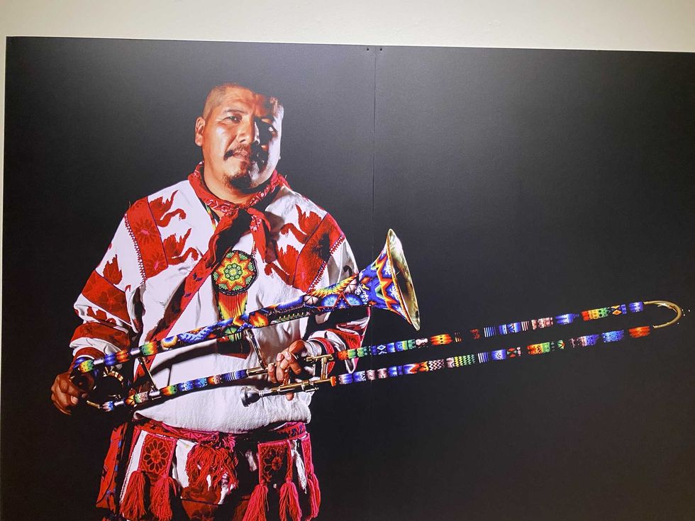 Man in traditional attire holding a vibrantly decorated trombone.