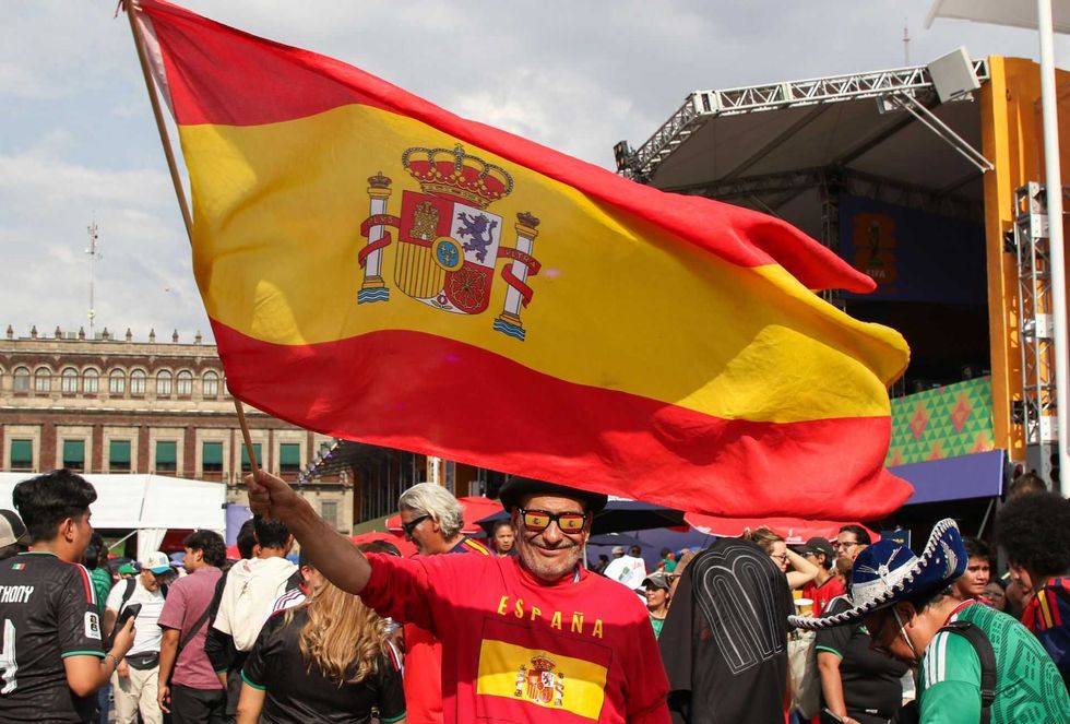 Man joyfully waves Spanish flag at a crowded event.