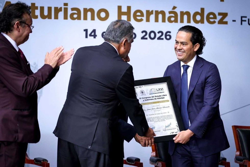 Man receiving a framed certificate on stage with clapping audience.