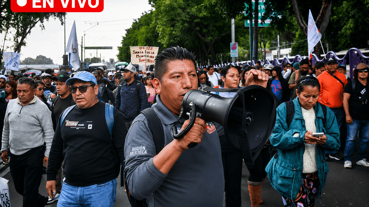 Man with megaphone leads protest march, crowd follows, "En Vivo" text above.