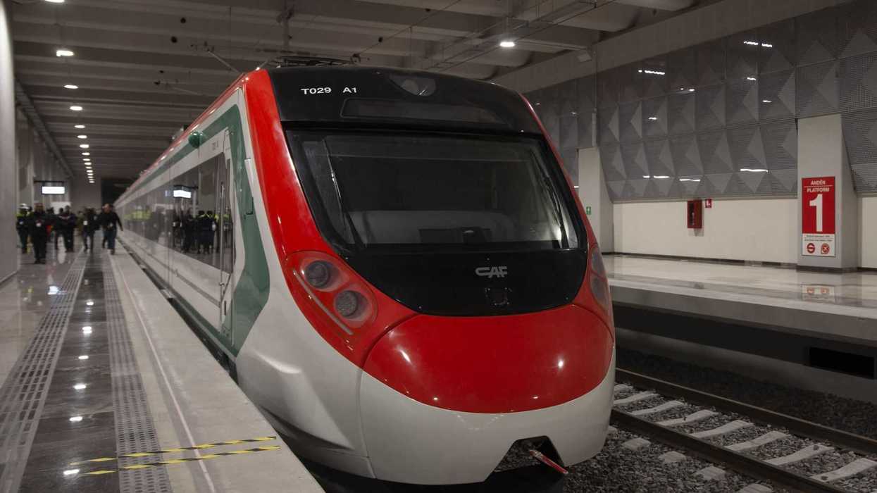 Modern red and white train stopped at a well-lit, spacious indoor station platform.