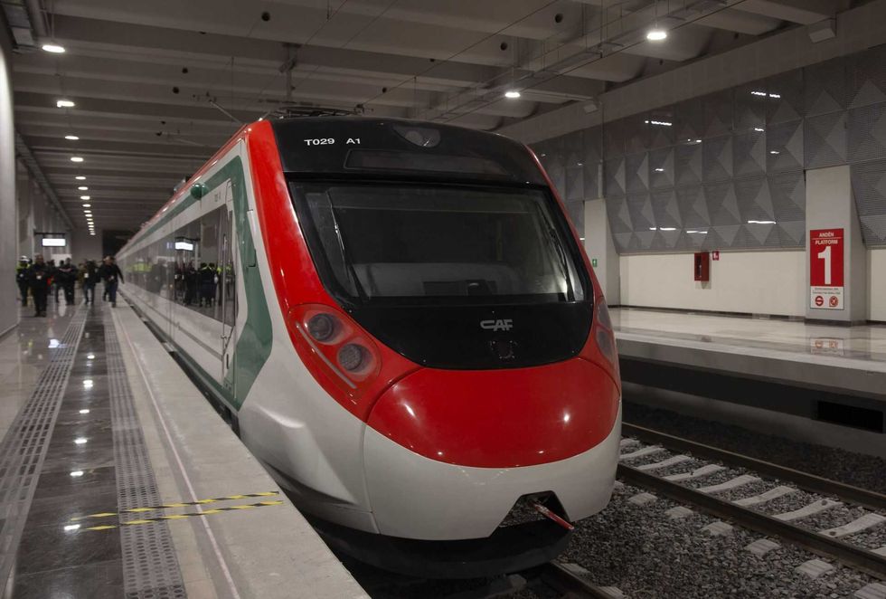 Modern train at an indoor station platform, with people in the background.
