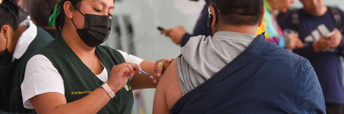 Nurse administering a vaccine to a man in a busy clinic setting.