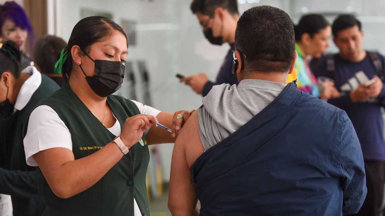 Nurse administering a vaccine to a man in a busy clinic setting.