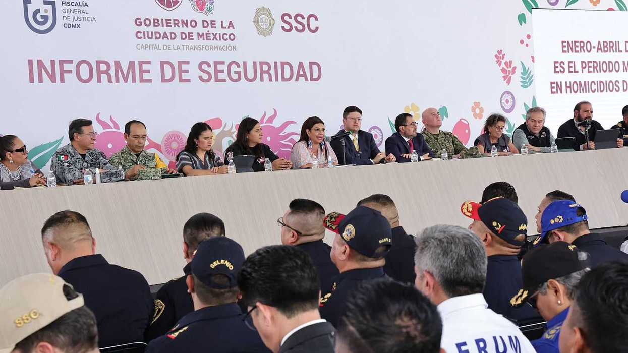 Officials at Mexico City security report meeting, seated at a long table with an audience.