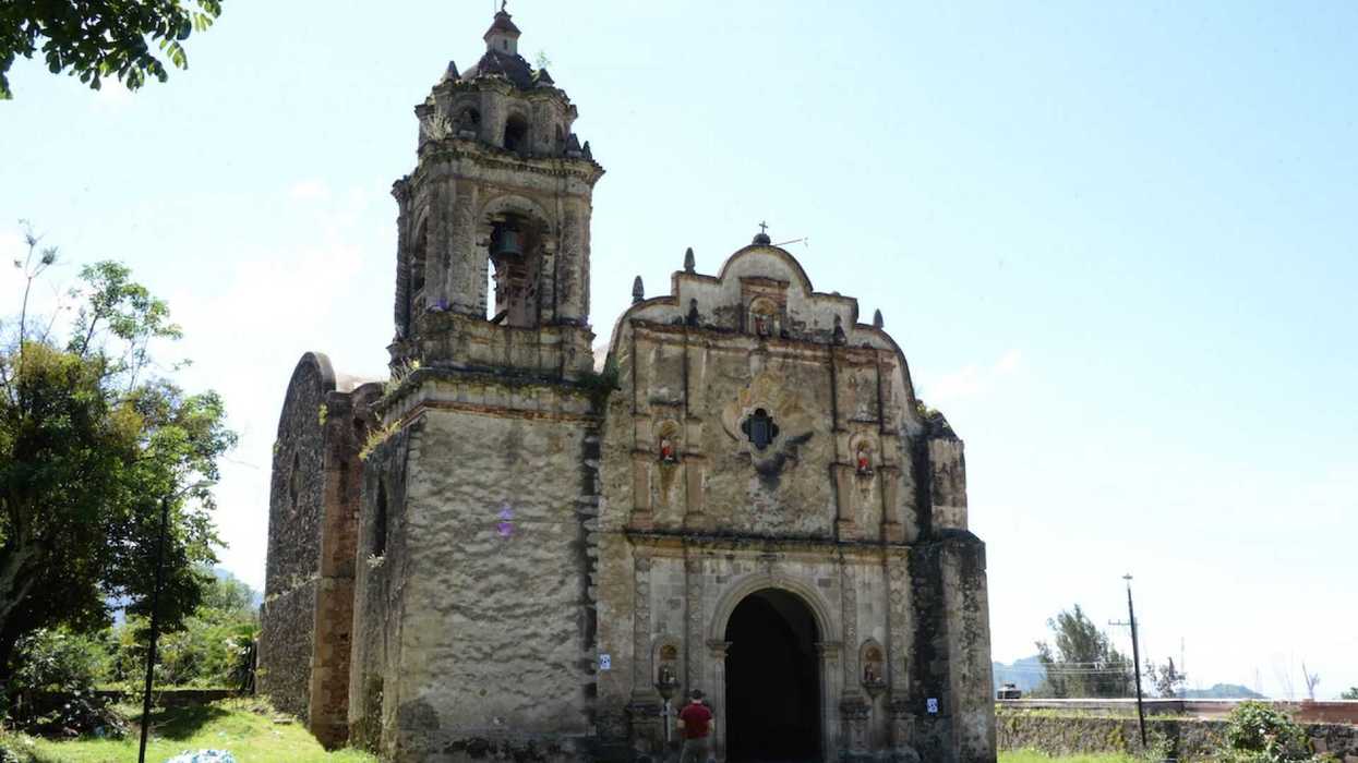 Old rustic church with bell tower under a clear blue sky.