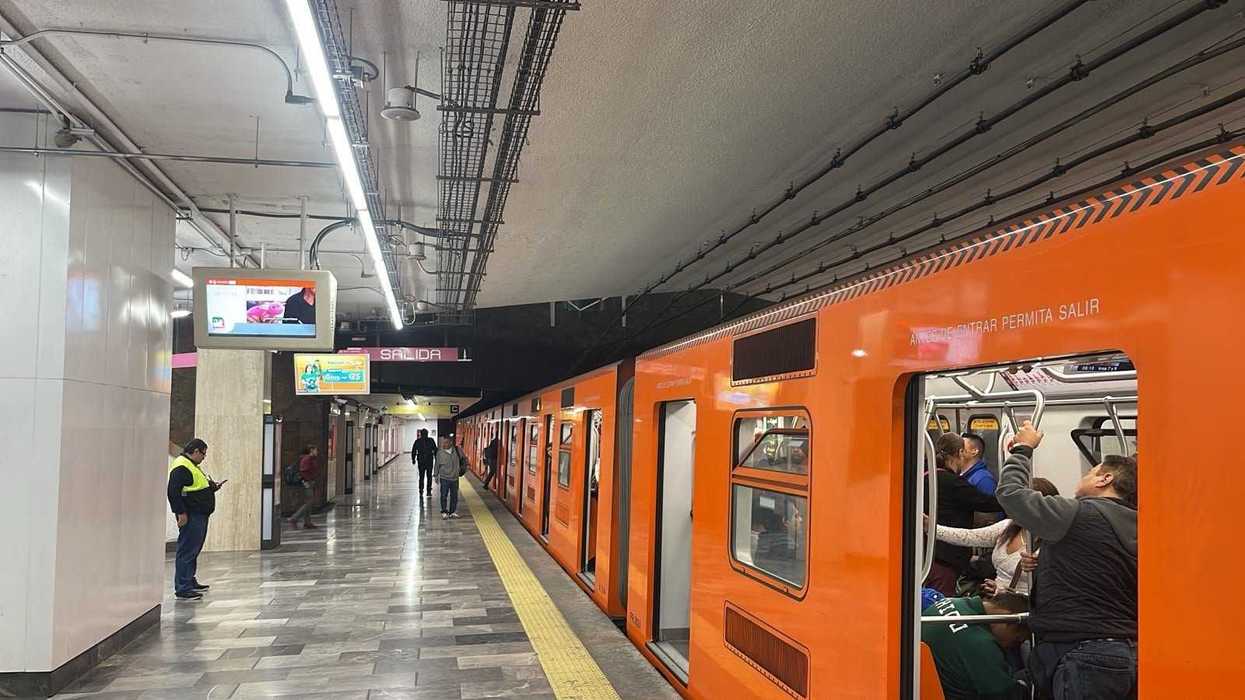 Orange subway train at a platform with passengers boarding and people waiting.