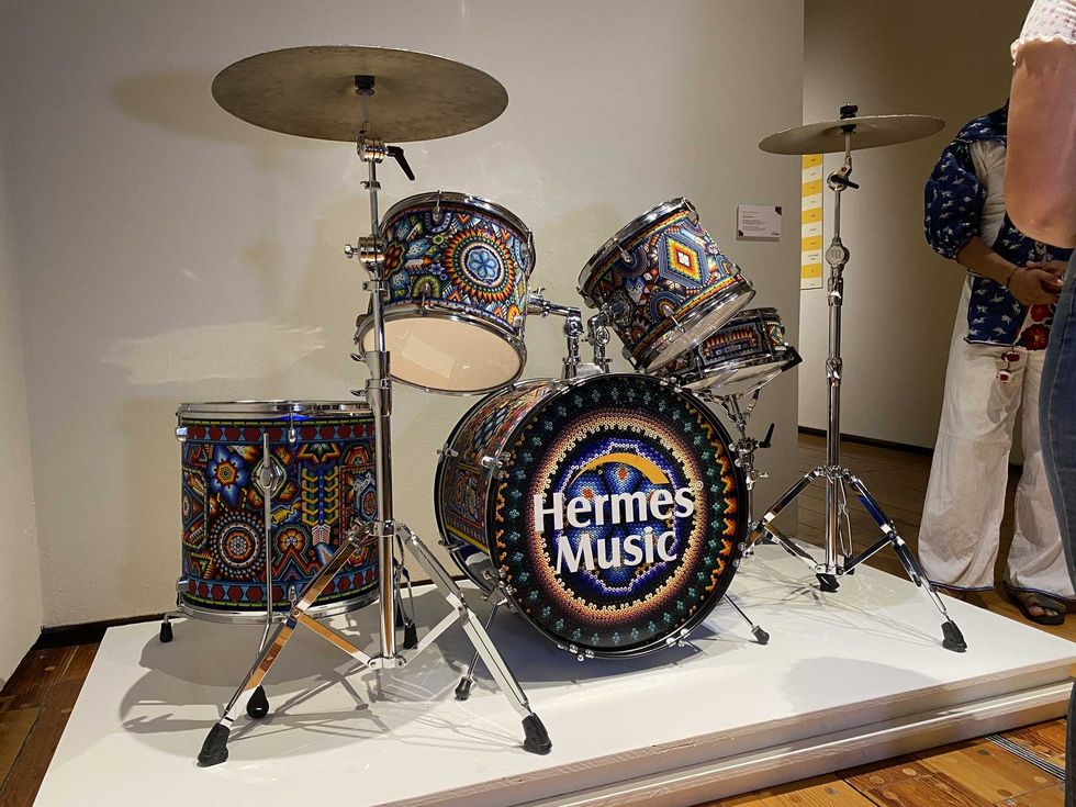 Ornate drum kit with intricate designs, labeled "Hermes Music," on display.
