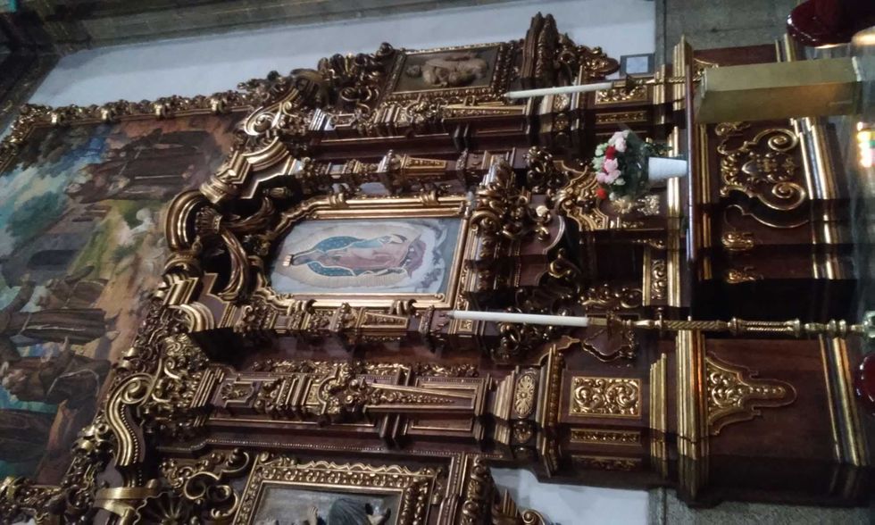 Ornate gilded altar with a religious painting and floral arrangement.
