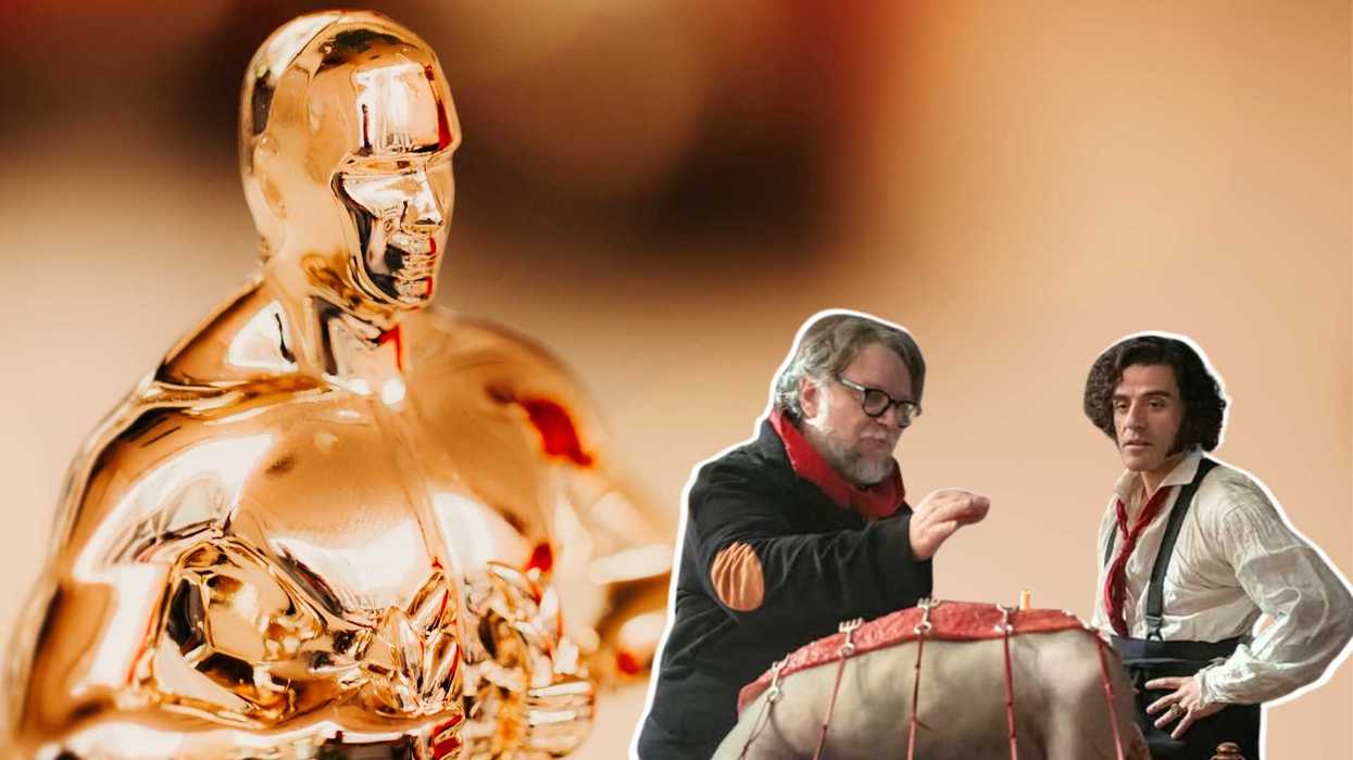 Oscar statue beside two men working on a model with a blurred background.