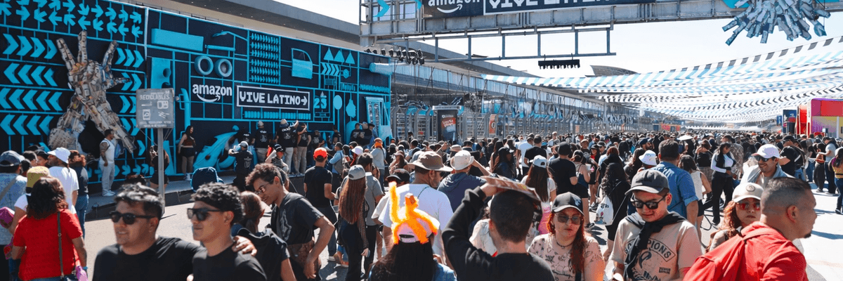 Outdoor festival crowd beneath "Vive Latino" sign with vibrant blue decor and urban art.