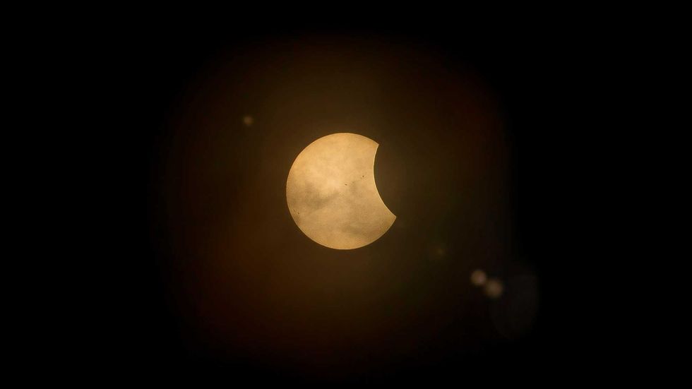 Partial solar eclipse with a dark, curved bite casting shadow on the sun.