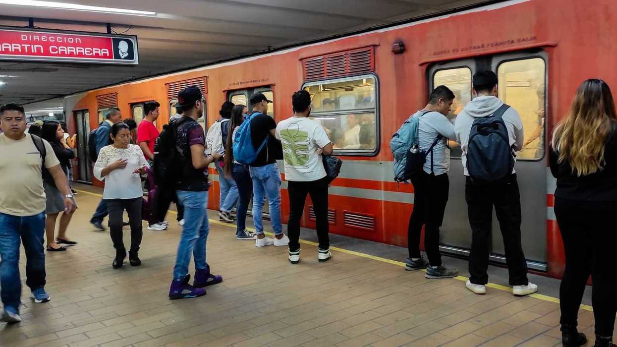 Passengers boarding an orange subway train at a station with "Martín Carrera" signage.
