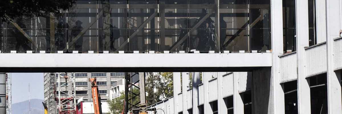 Pedestrian bridge and signage at San Antonio Abad metro station with construction below.