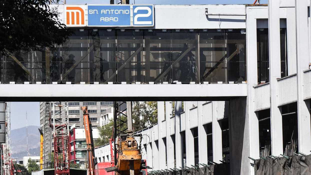 Pedestrian bridge and signage at San Antonio Abad metro station with construction below.