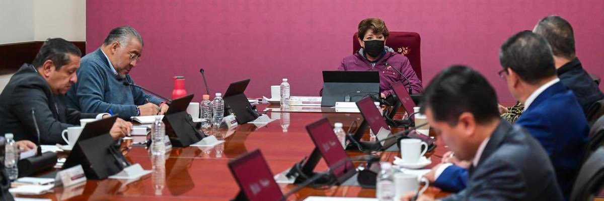 People at a conference table under a "Mesa de Paz Estado de México" sign.