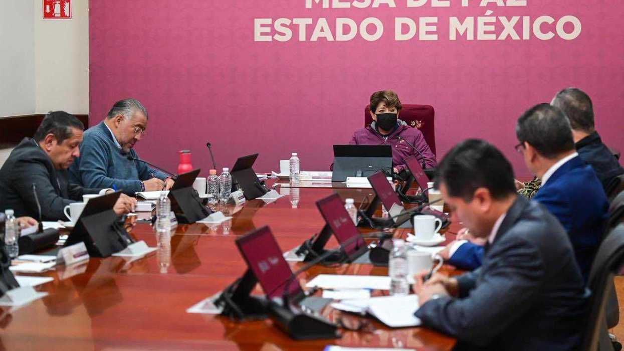 People at a conference table under a "Mesa de Paz Estado de México" sign.
