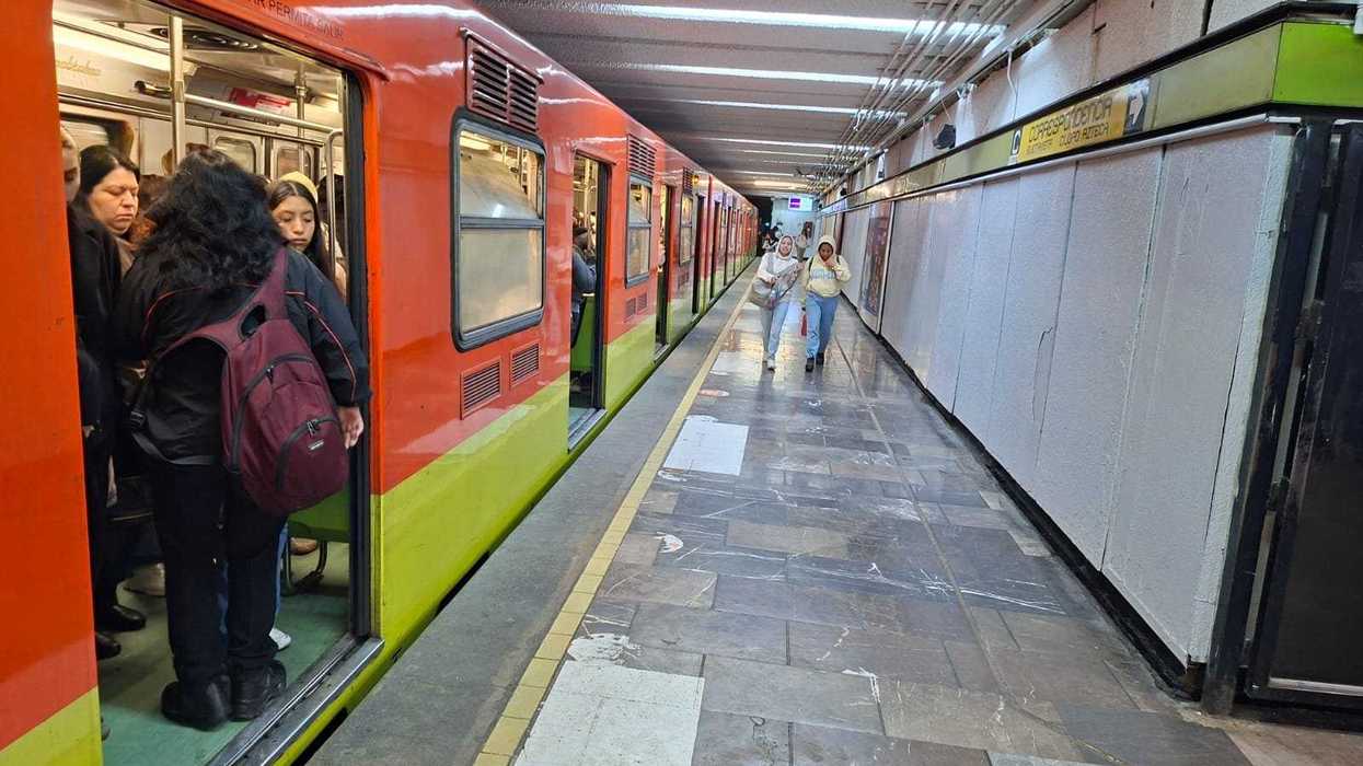 People boarding a subway train at a station platform with tiled flooring and overhead lights.