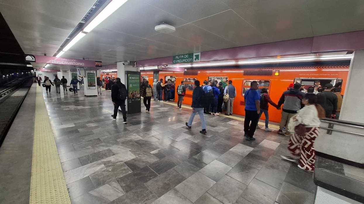 People boarding an orange subway train at a station platform.