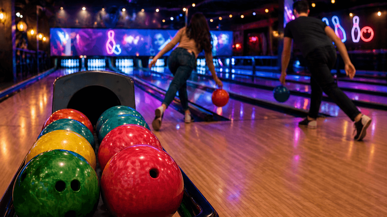People bowling with colorful balls in a dimly lit bowling alley.