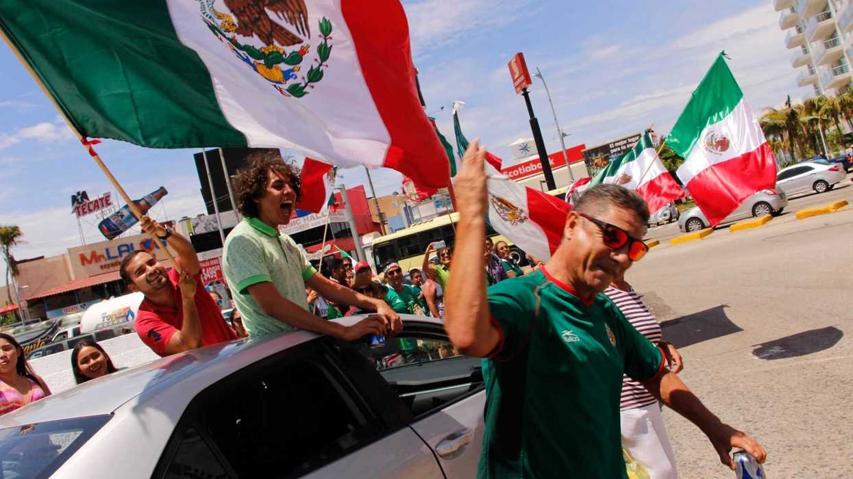 People celebrating with Mexican flags on a busy street.