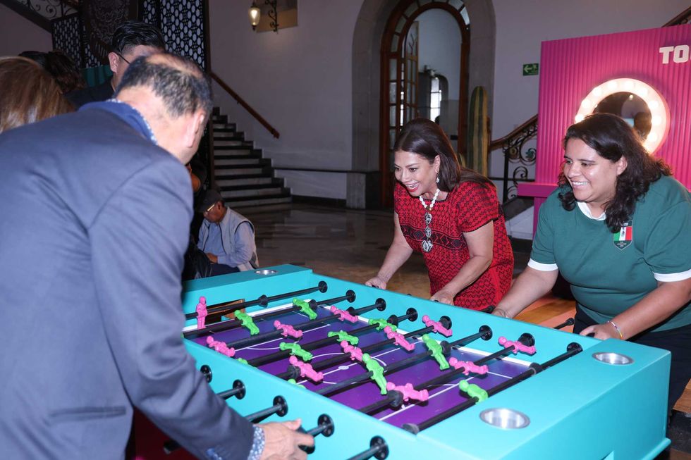 People enthusiastically playing foosball in a decorative indoor setting.