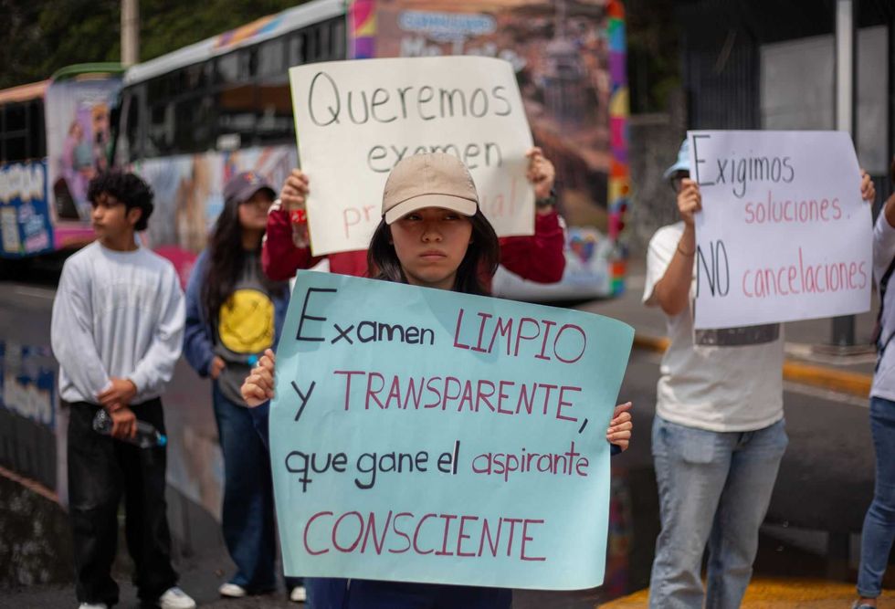 People holding protest signs demanding fair and transparent exams.