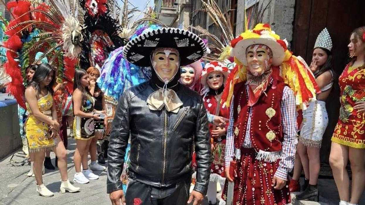 People in colorful traditional costumes and masks during a lively street festival.