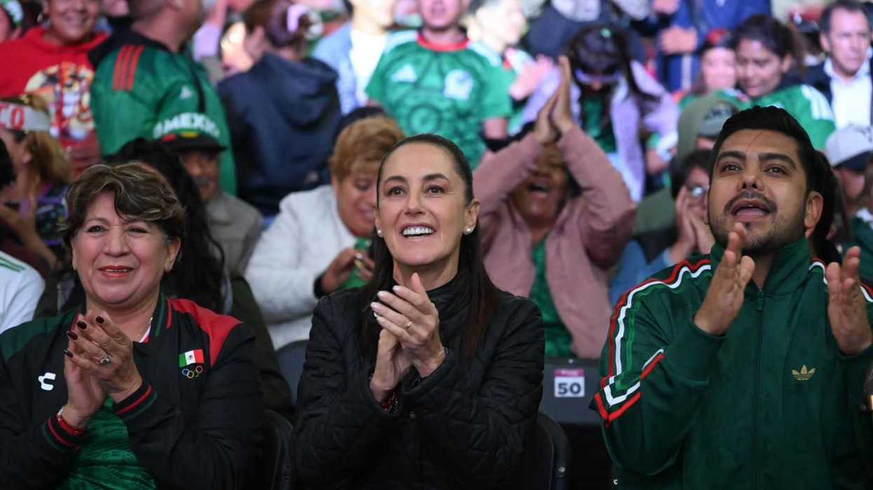 People in green jerseys clapping and cheering at a lively sports event.
