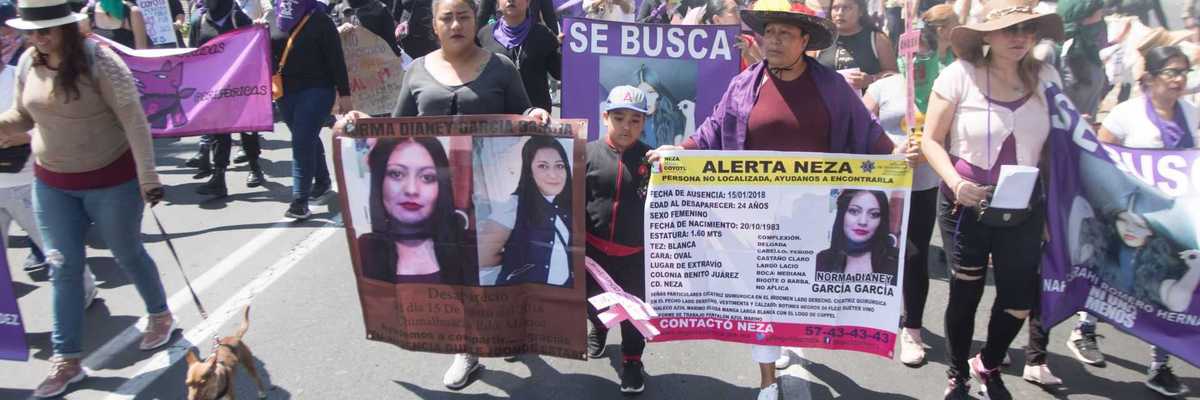 People marching with banners for missing persons, holding posters and placards in a protest.