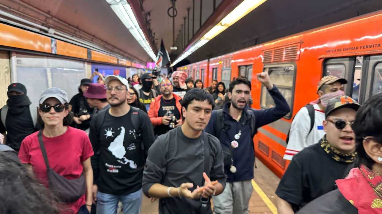 People protesting in a subway station with an orange train in the background.