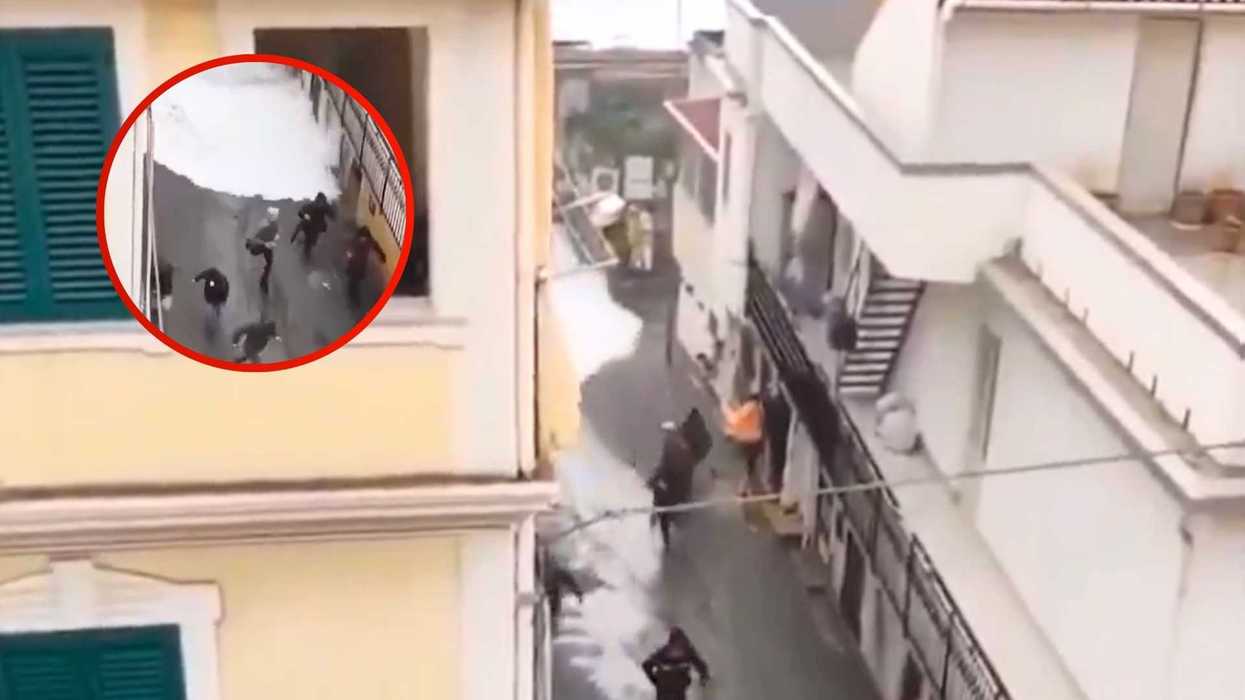 People running from a sudden foam flood in a narrow alleyway.