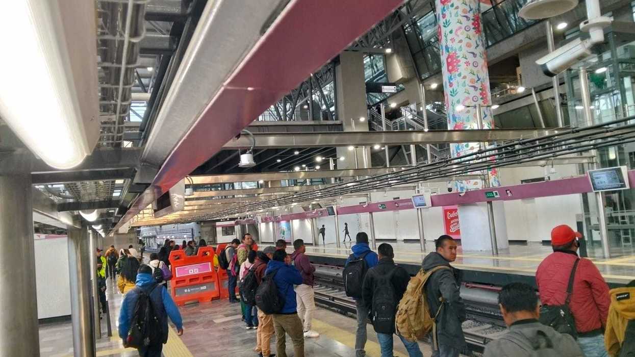 People waiting at a modern train station platform with colorful column decor.