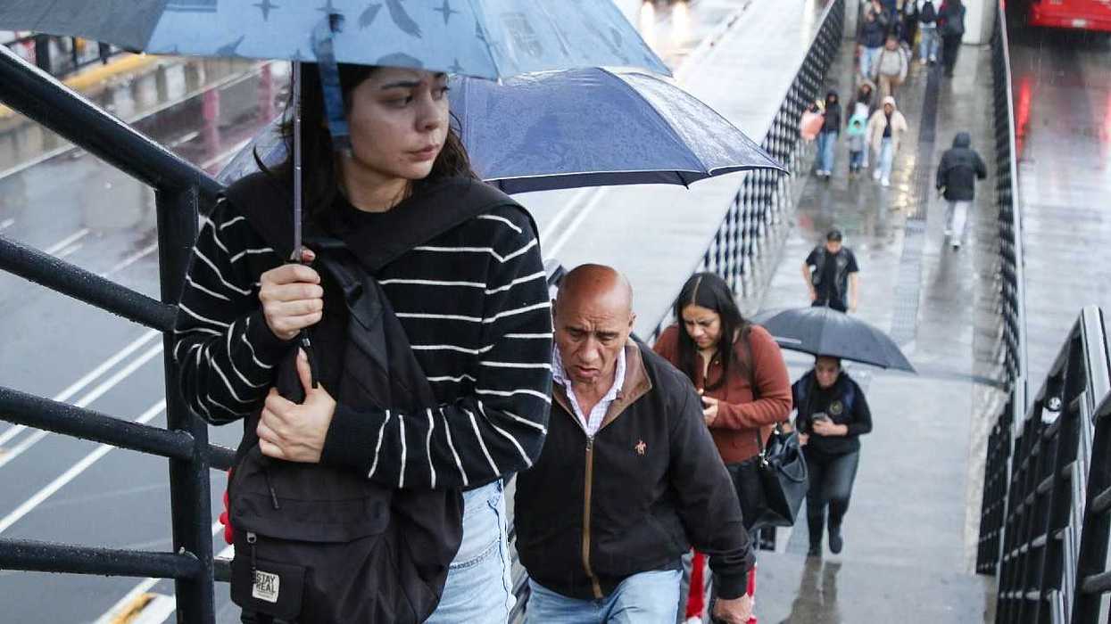 People with umbrellas walk up stairs on a rainy day.