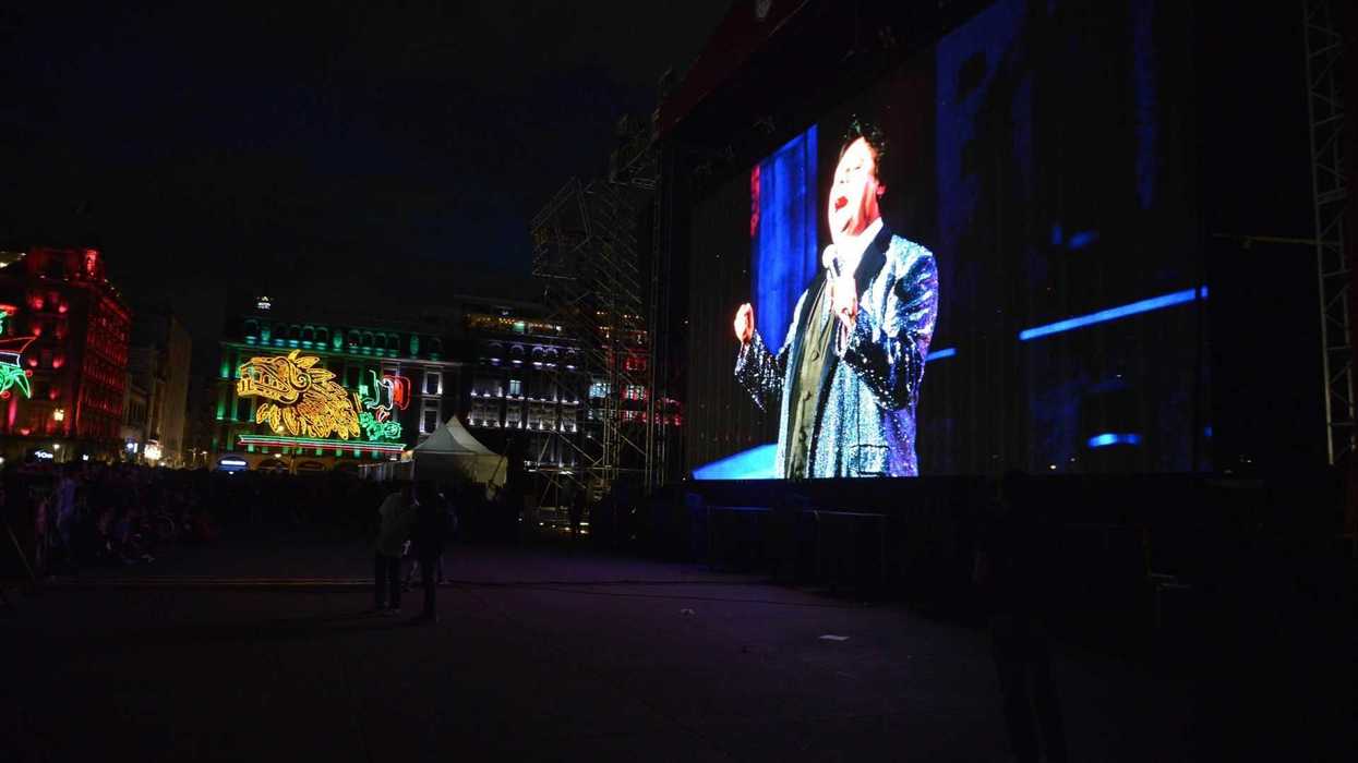 Performer singing on a large outdoor screen at night.