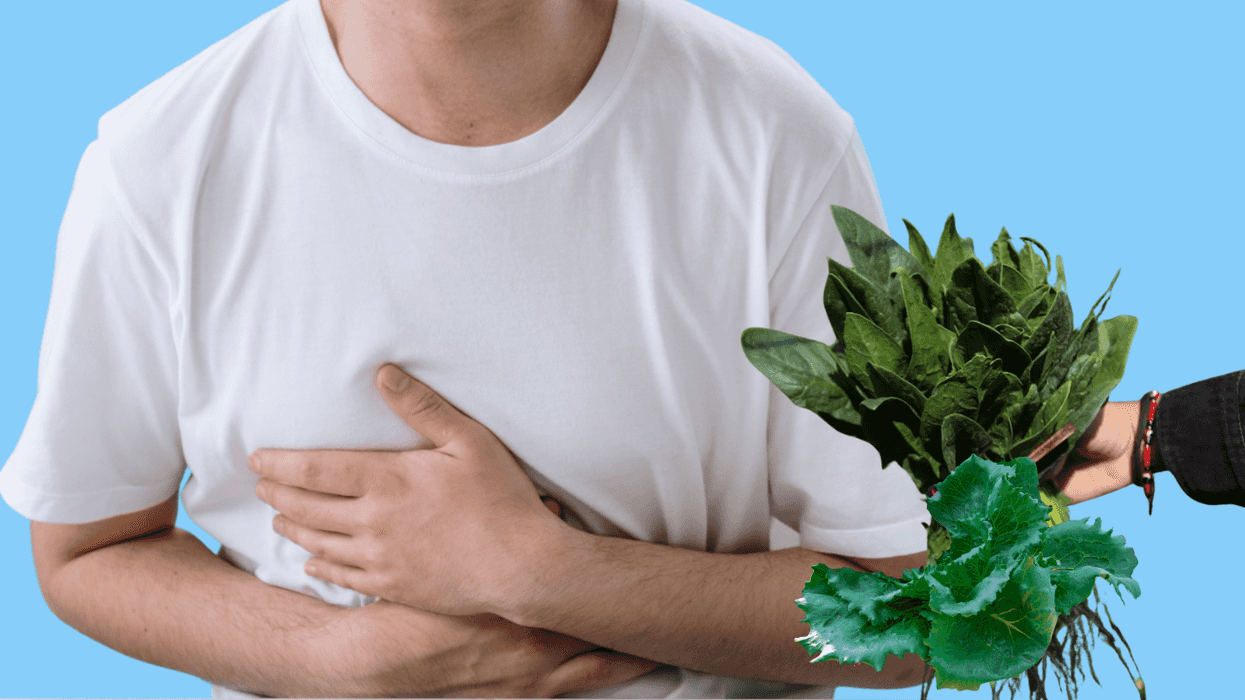 Person clutching stomach, bunch of greens offered, blue background.