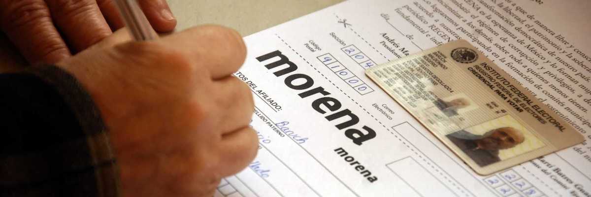Person filling out a form labeled "Morena" with an ID card placed on top.