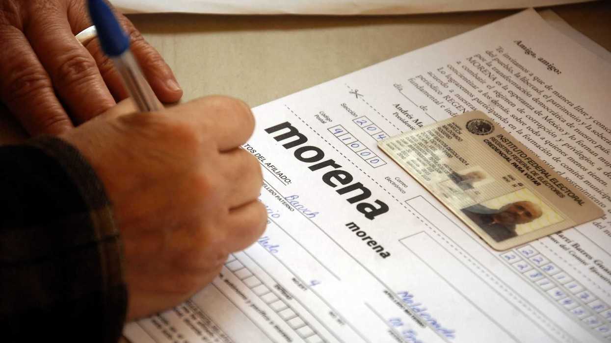 Person filling out a form labeled "Morena" with an ID card placed on top.
