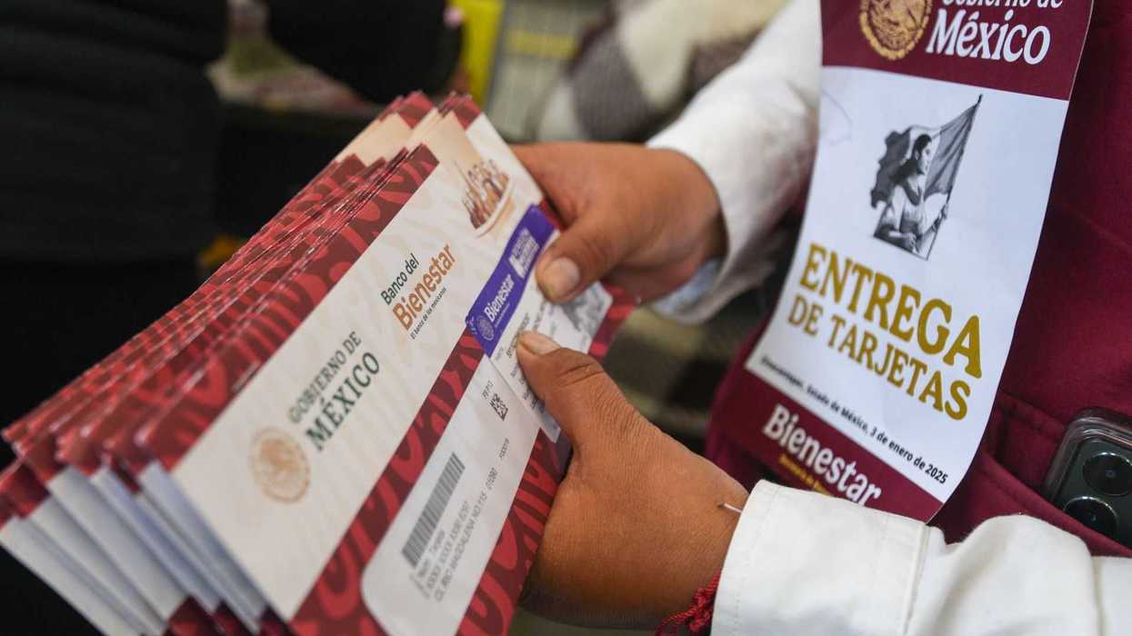 Person handling Banco del Bienestar cards, wearing "Entrega de Tarjetas" badge.