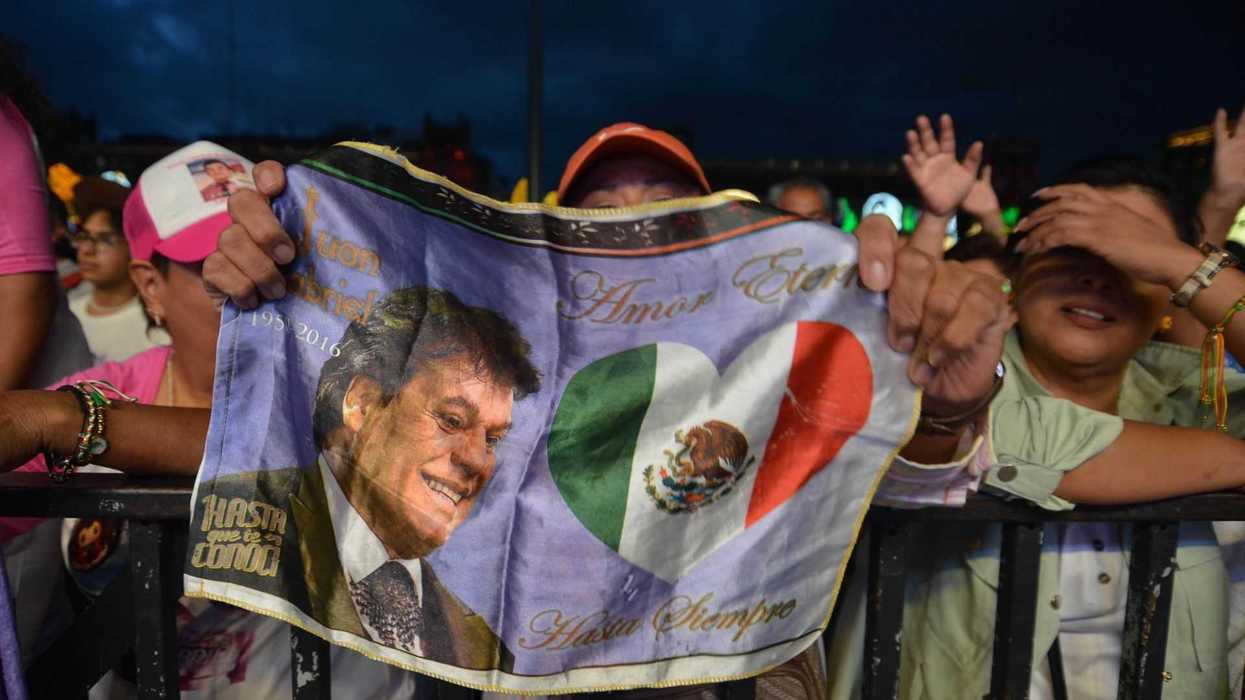Person holding a flag honoring a singer with a Mexican flag and "Amor Eterno" text.