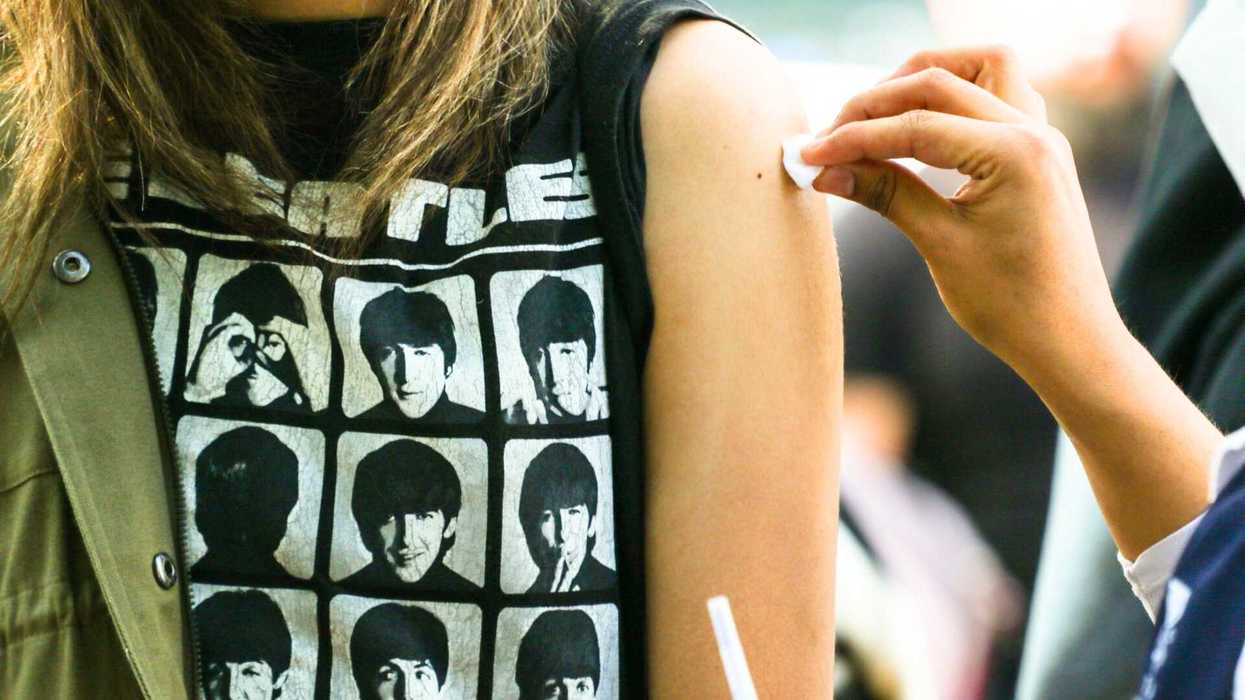 Person in Beatles shirt getting arm prepped for shot with cotton swab.