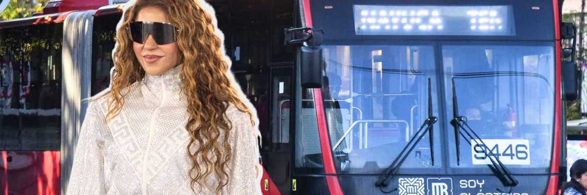 Person in sunglasses and white outfit in front of a red electric bus.