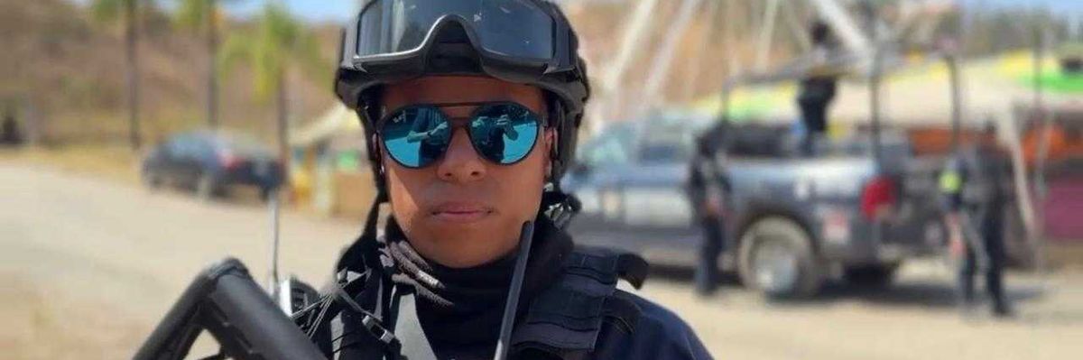 Person in tactical gear with a rifle, Ferris wheel in background, outdoors scene.
